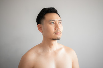 Fototapeta na wymiar Serious and stress face of Asian man in topless portrait isolated on gray background.