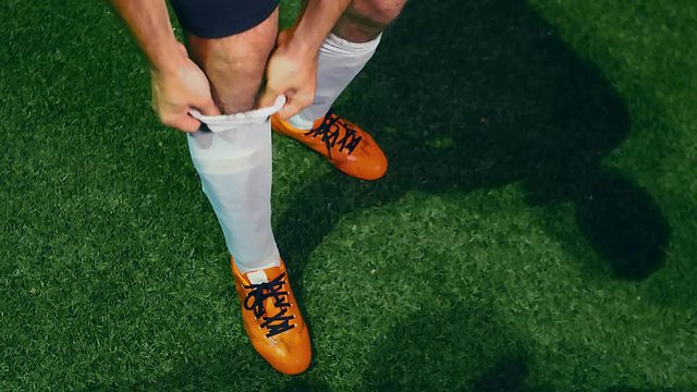 Professional soccer player adjusts his socks before the beginning of the match, 4k slow motion