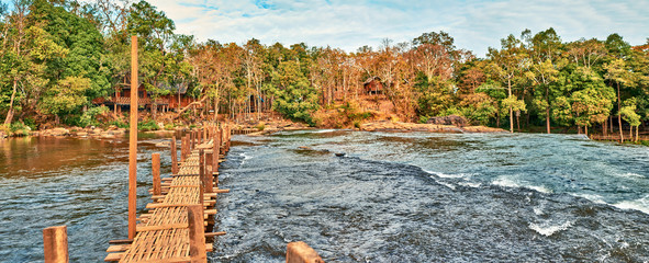 Wooden bridge over the stream in the tropical jungles panoramic view