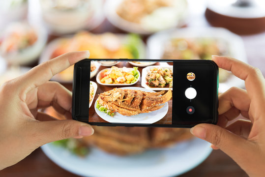 Woman taking a photo of food with smartphone in restaurant.