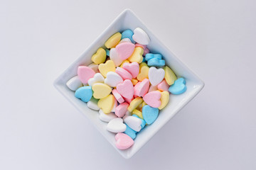 Valentine pastel colourful heart candies in a white square bowl