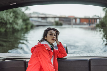 beautiful young woman in a red raincoat rides a private yacht. Stockholm, Sweden © Yuliya Kirayonak