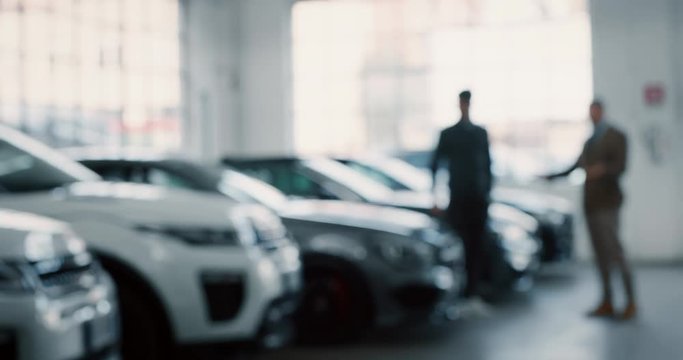 Dealer and new owner handshake after concluding a car deal in auto show or salon. Slow motion shot in 8K. Concept of car dealerships, used cars, car sale and rent, auto deal.