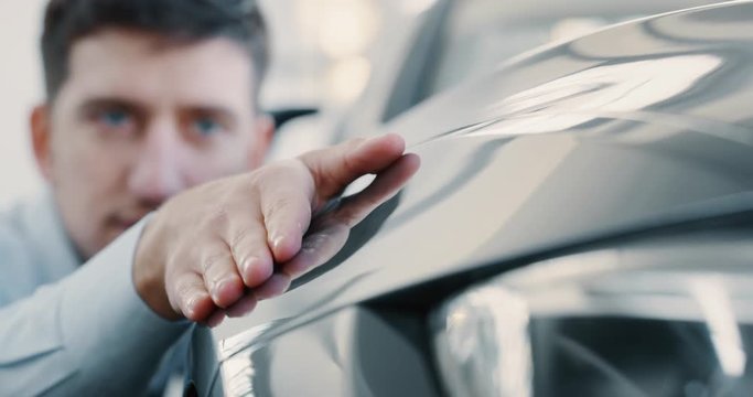 Close up young businessman checking anonymous just repaired in car auto body shop. Slow motion shot in 8K. Concept of auto deal, car dealerships, used cars, luxury cars