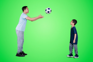 Father throwing a soccer ball to his son on studio
