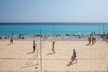 Fototapeta na wymiar Tourists and locals playing beach volleyball at Nice beach, France