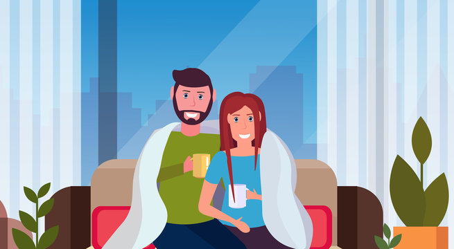 couple drinking tea man woman sitting on couch under cozy plaid happy lovers relaxing modern apartment interior cityscape male female characters portrait horizontal