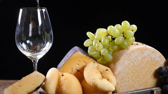 Restaurant cheese art. Variety of hard cheese put in a beautifully composition. Wine is pouring into a flass in slow motion. Wine and appetizer concept. Luxury restaurant concept. Food art. hd