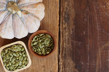 Pumpkin seed and pumpkin fruit in wooden bowl on classic wooden table background
