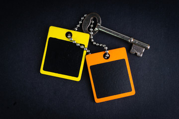 Key and wooden tag on black background with selective focus and crop fragment. Business and copy space concept