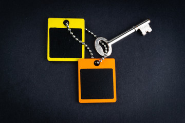 Key and wooden tag on black background with selective focus and crop fragment. Business and copy space concept