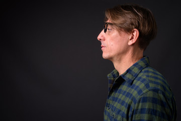 Profile view of mature handsome Italian man against gray background