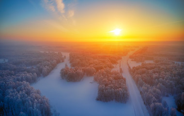 Sun over siberian furest under the snow at morning time. Siberian rural winter sunrise landscape with birch trees covered with hoarfrost.