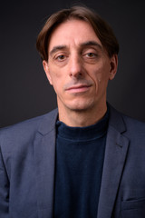 Face of mature handsome Italian businessman against gray background
