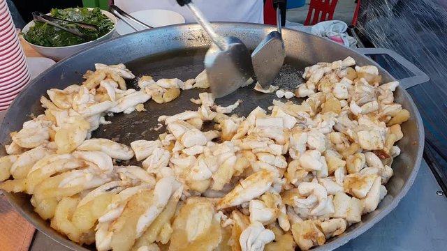 fried squid eggs cooking in a large pan at Thai street food market 