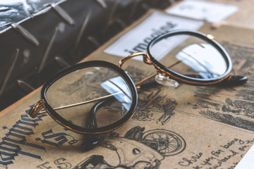 closeup old glasses and book on wooden table with soft-focus and over light in the background