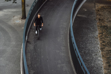 Man Riding Bicycle Across Bridge at Sunset