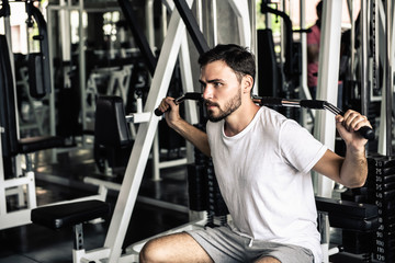 Handsome man is rowing exercise with bodybuilder machine in fitness club.,Portrait of strong man doing working out calories burning in gym., Healthy and fitness sport gym concept.