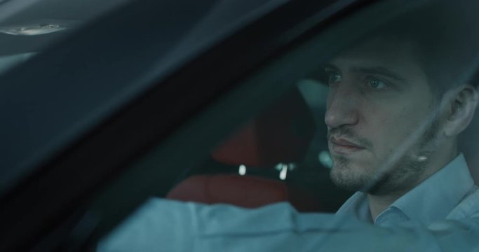 Portrait of young businessman is driving a new anonymous car just bought from auto deal. Slow motion shot in 8K. Concept of passion for driving cars and engines, car dealerships, used cars, luxury car