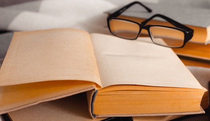 Stack of open vintage books with glasses