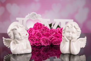 A bouquet of pink roses against a black background with love angels