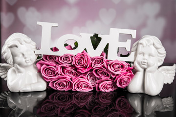A bouquet of pink roses against a black background with love angels