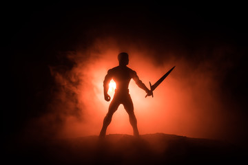 Medieval battle scene. Silhouettes of figures as separate objects, fight between warriors on dark toned foggy background. Night scene.
