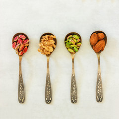 Different types of nuts lie in spoons. Assorted walnuts, almonds and pistachios. Concept- healthy diet,  full source of vegetable protein in vegetarianism and raw food.