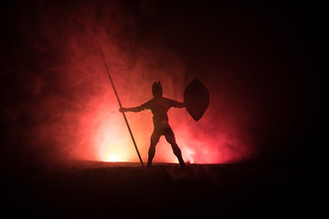 Medieval battle scene. Silhouettes of figures as separate objects, fight between warriors on dark toned foggy background. Night scene.