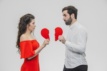 Portrait of an Excessive Couple. Conducting two parts of the heart paper. Isolated on a white background.