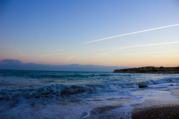 Golden Hour Serenity: Sun Setting Over Mediterranean Waves and Sky Trails in Cyprus