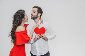 Family, holidays, Valentine's Day. Love people concept - a big plan. Hold the red paper heart. White background. Dressed in a white shirt and a red dress.