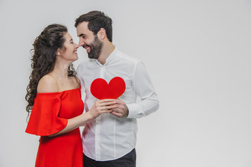 Family, holidays, Valentine's Day. Love people concept - a big plan. Hold the red paper heart. White background. Dressed in a white shirt and a red dress.