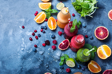 Colorful detox smoothie in bottles, summer diet fresh drink, red, green, yellow smoothie with berries and fruits