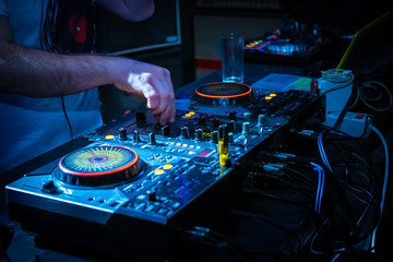 Obraz premium DJ music console and laptops in bright colors of light in night club bright blue background
