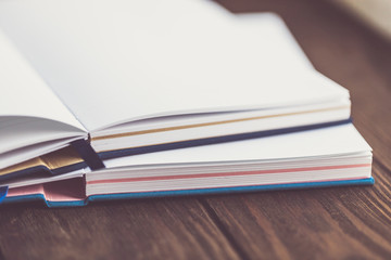 Lifestyle photo of an empty open paper notebooks  on a wooden table in a workspace.