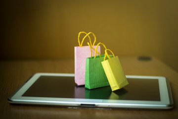 Colorful paper bag on tablet. Consumers can be shopping online directly from Internet. Ideas about online shopping and electronic commerce.