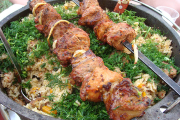 Barbecue meat on skewers and white rice in an iron pot. Top view, flat lay.