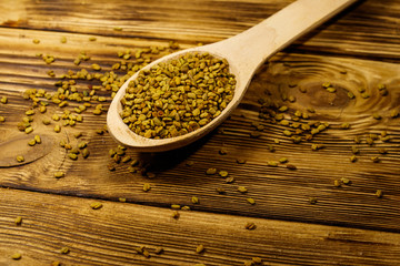 Fenugreek seeds in wooden spoon on wooden table