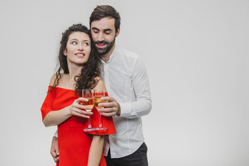 Loving young couple drinks champagne. On a white background. Dressed in red dress and white shirt.