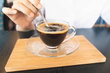 Women white shirts make black coffee on brown wood desk in cafe. vintage tone. close up hand. relax concept.