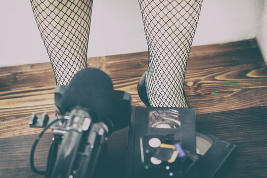 video camera cassette, flash drive lying on the table. girl in tights in a large cage. pornography photography concepts