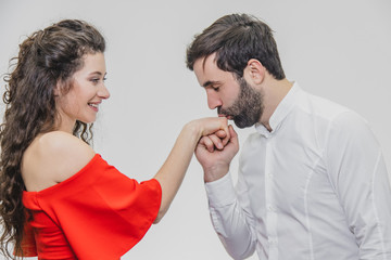 Young pretty boy kisses his beautiful girl beautifully. During this girl dressed in a red dress, a guy in a white shirt.
