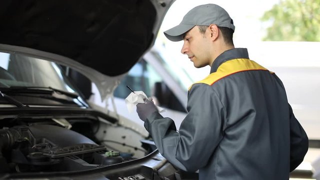 Car mechanic checking oil in a van engine