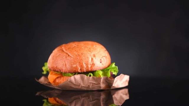 Cheeseburger rotated on black background. Fresh Hamburger on fresh buns with succulent beef and fresh salad ingredients isolated on black. Slow motion. 3840X2160 4K UHD video footage