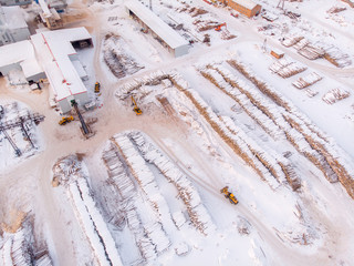 Industrial photo, storage of wooden logs under the snow at a sawmill. Top view