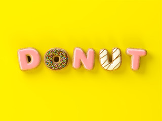 Fototapeta premium Delicious donuts with shape of letters glaze on yellow background 3D illustration