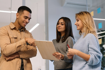 Group of happy multiracial business people working project, planning strategy, talking, discussion creative idea in modern office. Smiling colleagues meeting, collaborate, using sticky notes and scrum