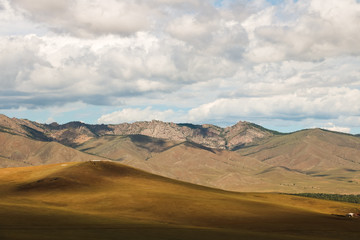 Mongolian countryside with dramatic mountain range and cloudy sky as seen from top of Genghis Khan Statue Complex near Ulaanbaatar (Mongolia, Asia)