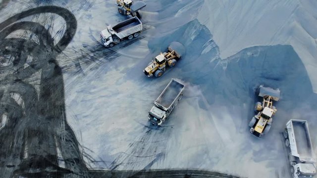 AERIAL. Top angle view of big career and excavators pours sand into the truck. On the construction site top view. Shooting from the drone.